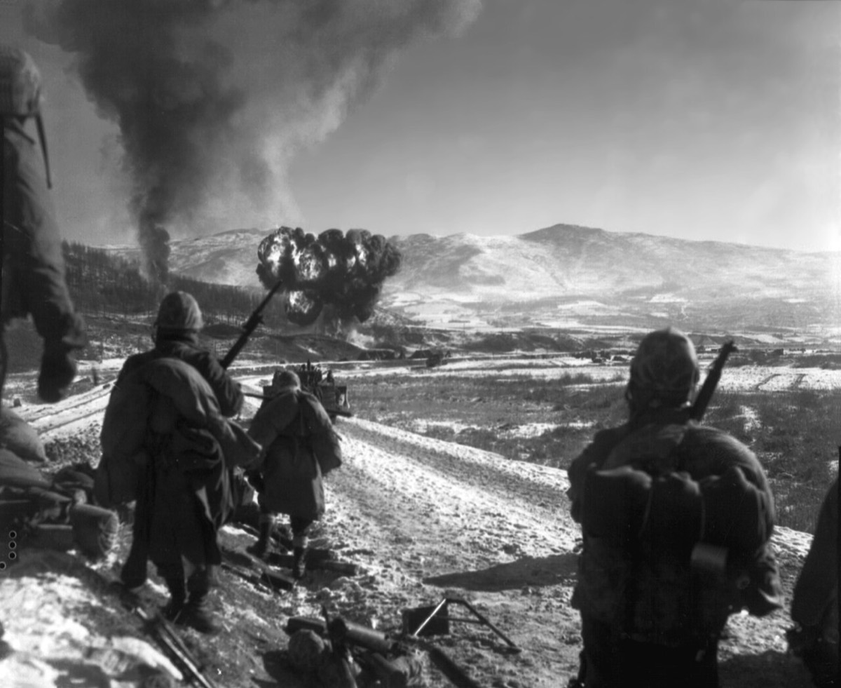 Original caption: U.S. Marines move forward after close-air support flushes out the enemy from hillside trenches. Billows of smoke rise from the target areas.