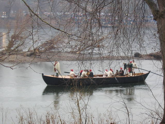 Boatmen row a Durham boat across the Delaware River after reenacting Washington's crossing of the Delaware River.